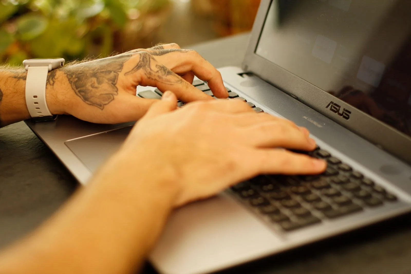 A person working at their laptop, actively typing and focused