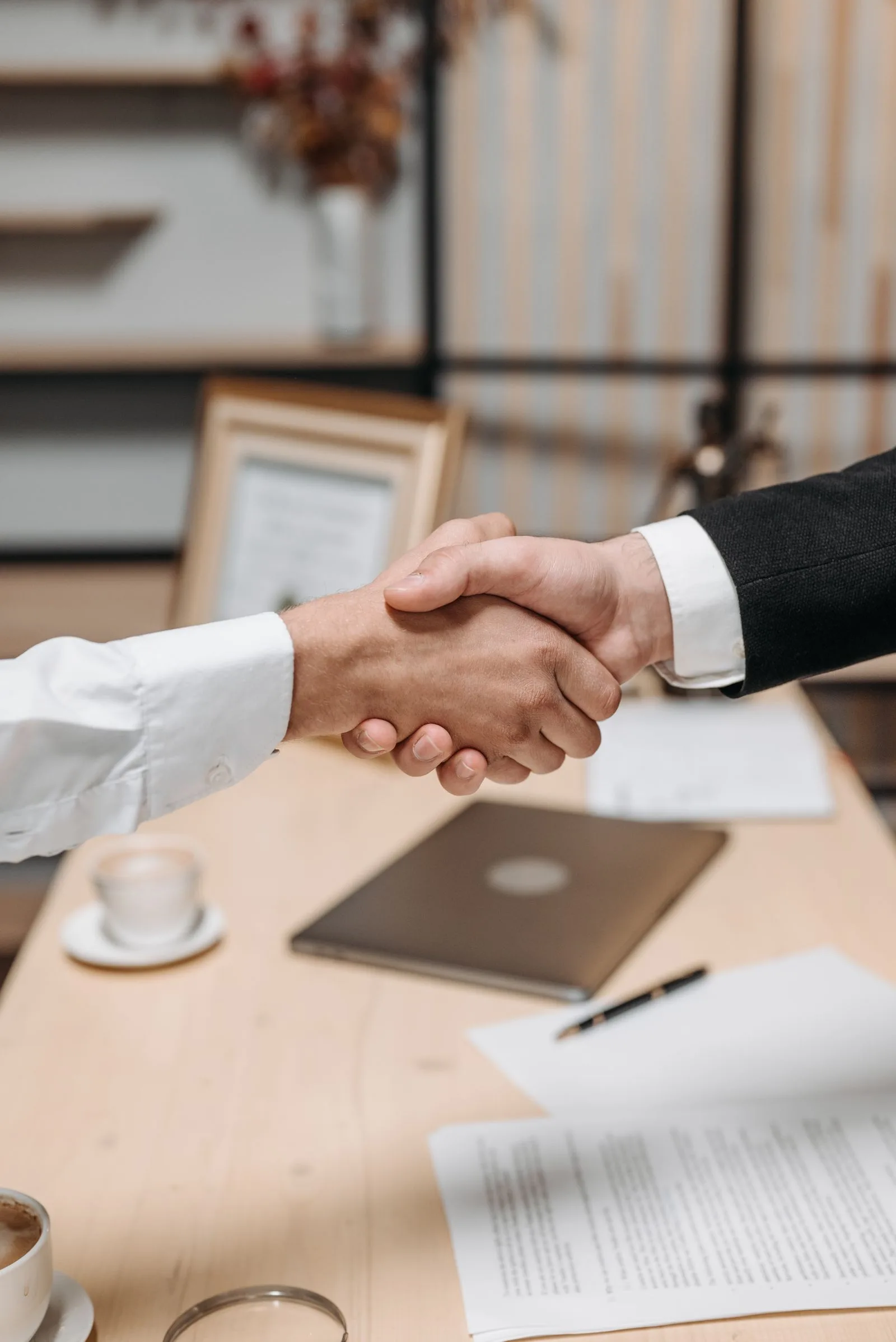 Interviewer and candidate shaking hands across a desk during a job interview